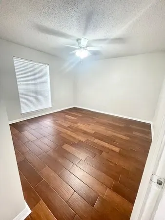 en empty room with wooden floor and fan