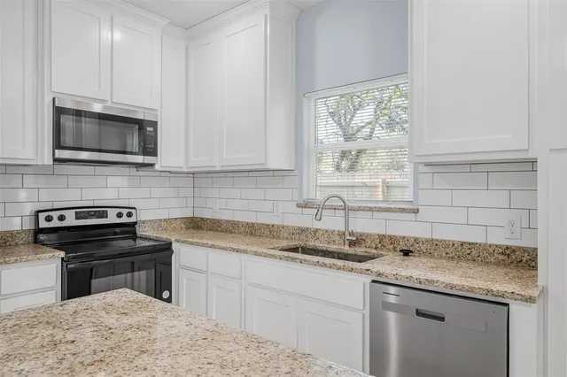 a kitchen with granite countertop a sink stainless steel appliances and cabinets
