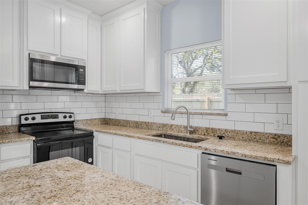 3005 Blackjack Lane Granbury, TX 76048 - Photo 20 of 30 a kitchen with granite countertop a sink stainless steel appliances and cabinets