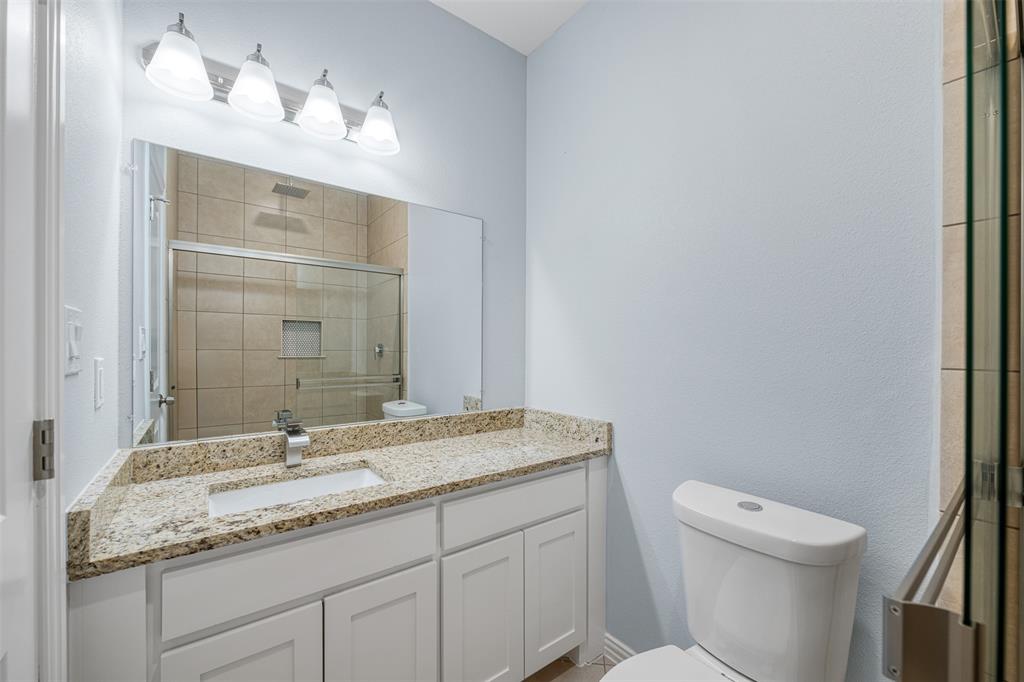3005 Blackjack Lane Granbury, TX 76048 - Photo 24 of 30 a bathroom with a granite countertop sink a toilet and a mirror