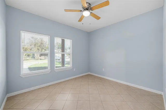 an empty room with chandelier fan and windows