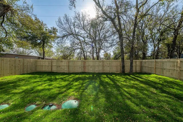 a view of a yard with a fence and trees