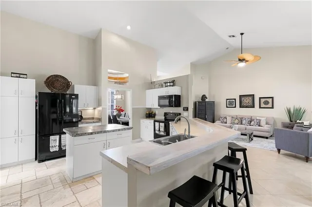 a kitchen with stainless steel appliances kitchen island granite countertop a sink a stove and chairs