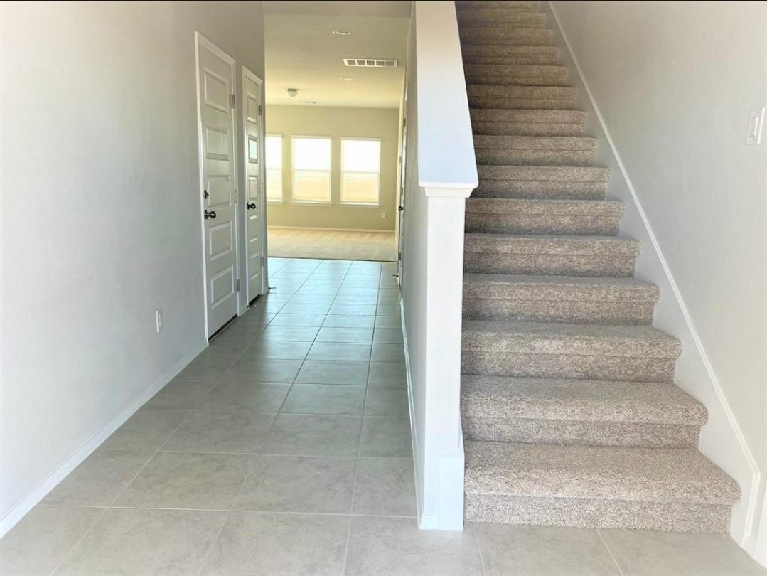 2771 Winding Creek Road Kyle, TX 78640 - Photo 3 of 24 A welcoming entryway with durable tiled flooring transitions to carpeted stairs, leading to upper levels.