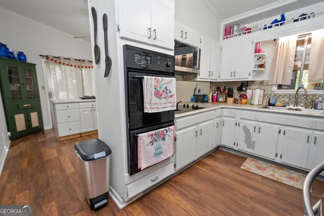 a kitchen with granite countertop a sink appliances cabinets and wooden floor