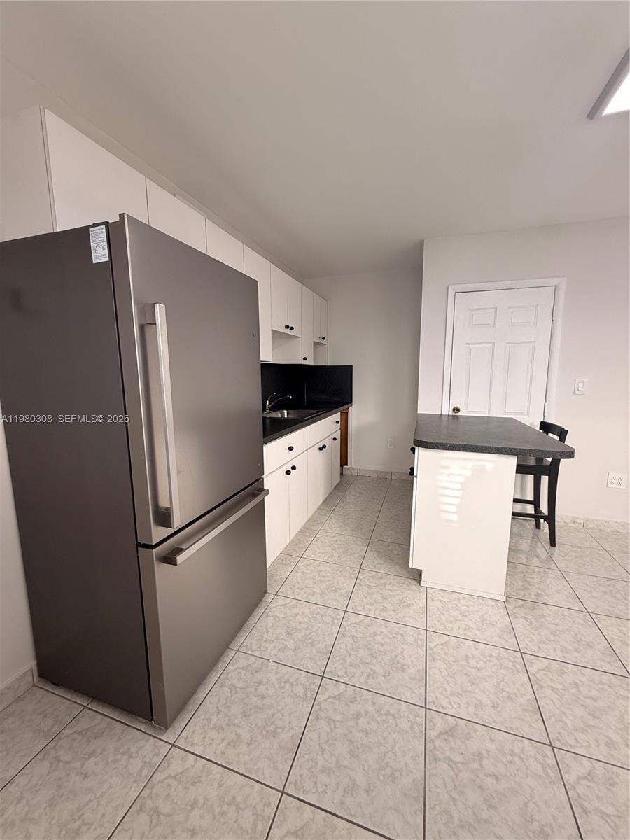 3666 Southwest 24th Terrace, Unit R Miami, FL 33145 - Photo 2 of 10 a kitchen with granite countertop a refrigerator and a stove top oven