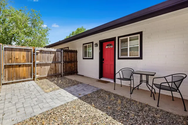 a backyard of a house with wooden table and chairs