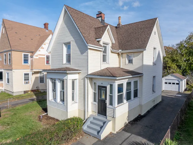 a view of a white house with a yard table and chairs
