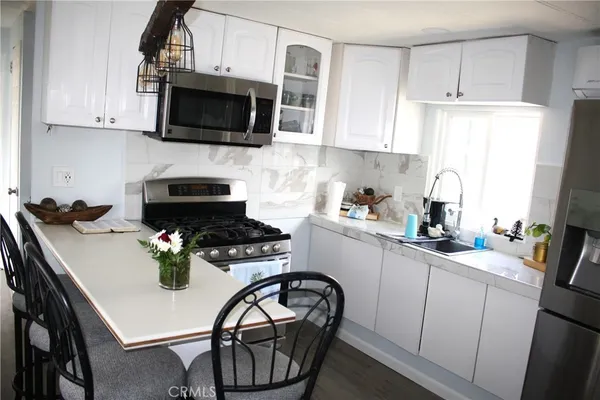a kitchen with stainless steel appliances granite countertop a refrigerator a sink a stove and white cabinets