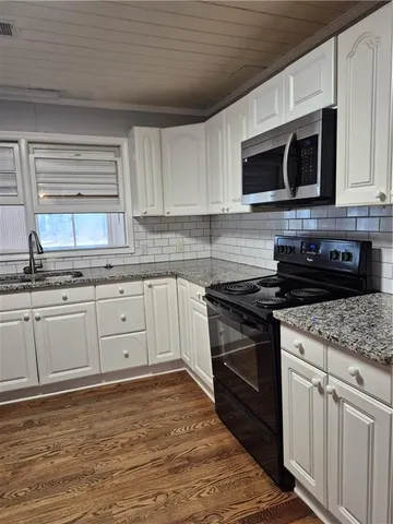 a white kitchen with granite countertop stainless steel appliances