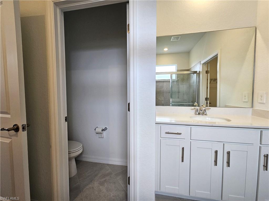 2168 Dragonfruit Way Naples, FL 34120 - Photo 15 of 27 a bathroom with a granite countertop sink a toilet and a mirror