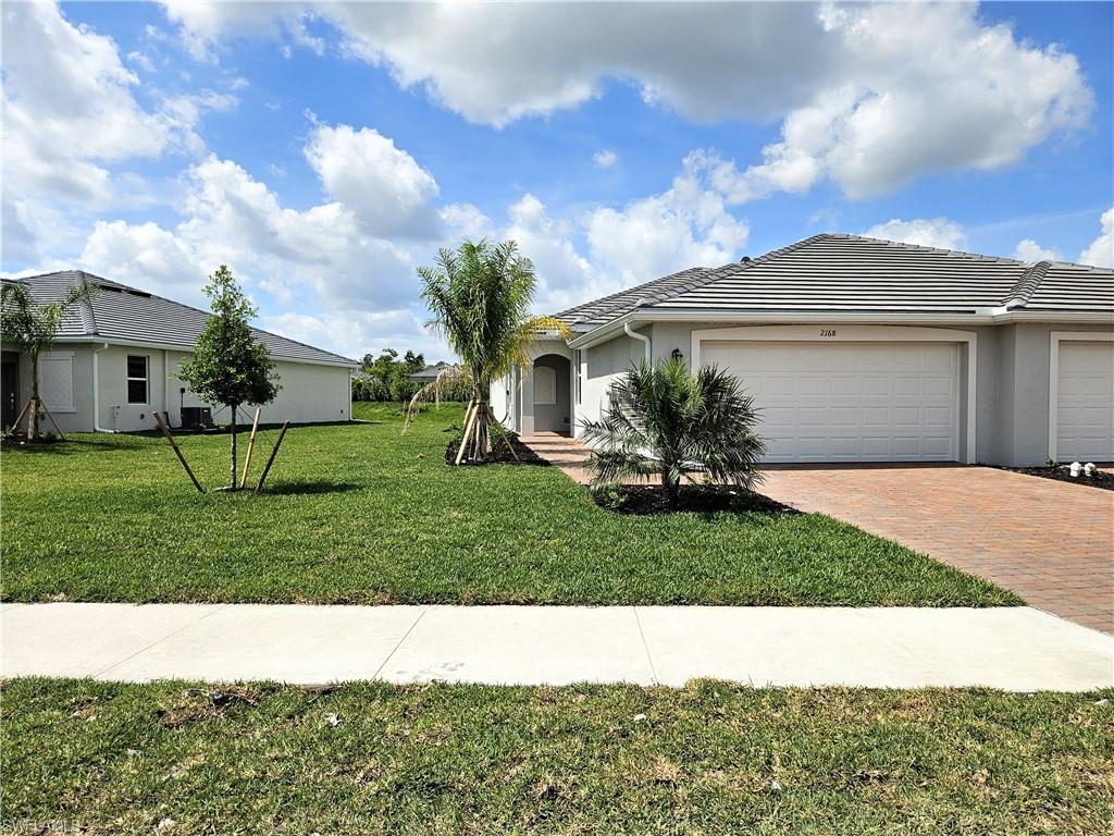 2168 Dragonfruit Way Naples, FL 34120 - Photo 21 of 27 a view of a white house with a big yard and a large tree