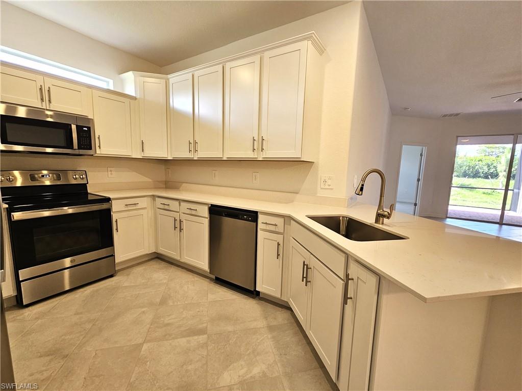 2168 Dragonfruit Way Naples, FL 34120 - Photo 8 of 27 a kitchen with a sink a stove and cabinets