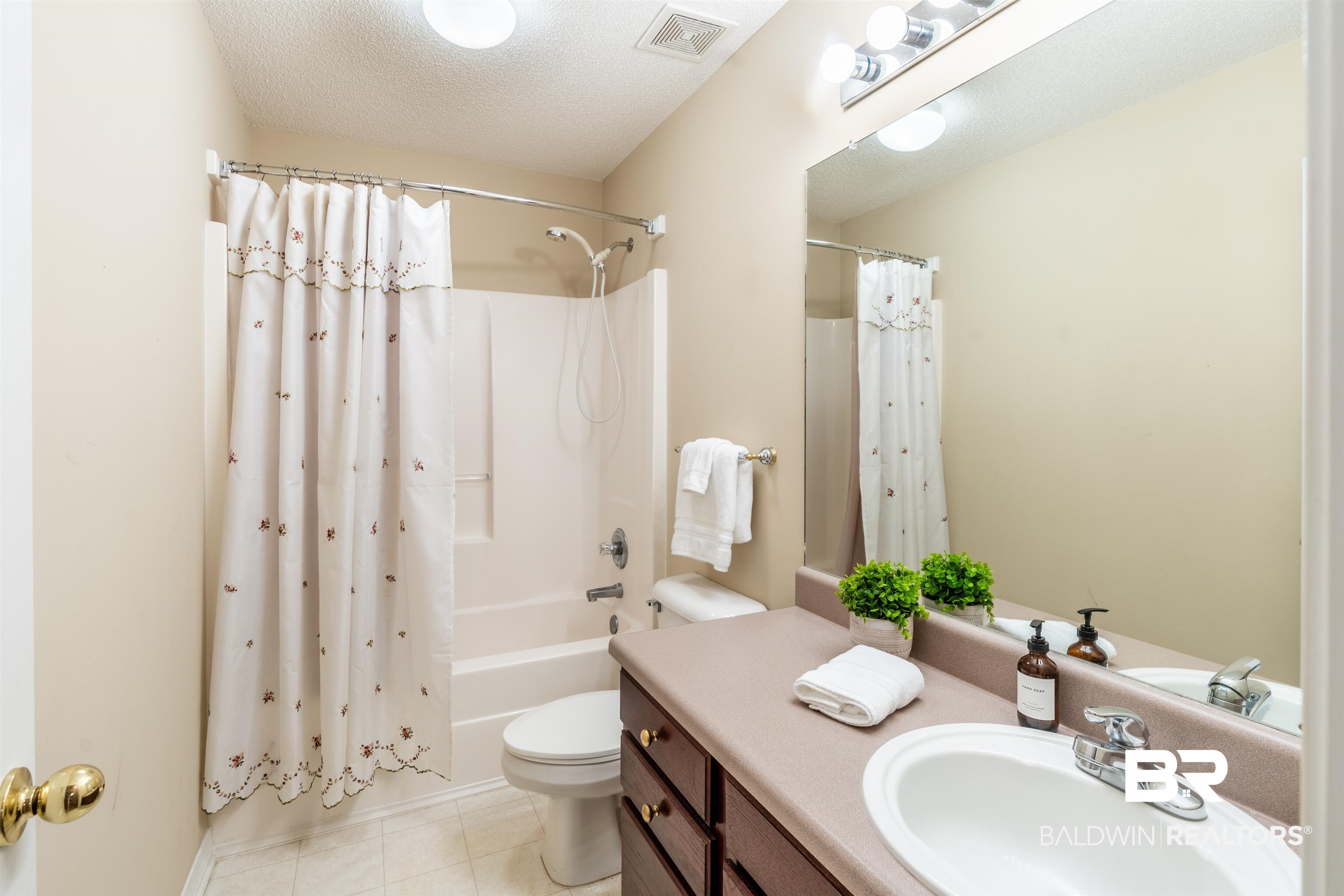 1784 Harrington Way Mobile, AL 36695 - Photo 15 of 18 Full bathroom featuring vanity, tile patterned flooring, a textured ceiling, shower / bath combo with shower curtain, and toilet