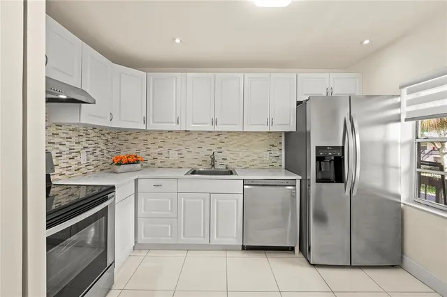 a kitchen with stainless steel appliances granite countertop a refrigerator sink and stove