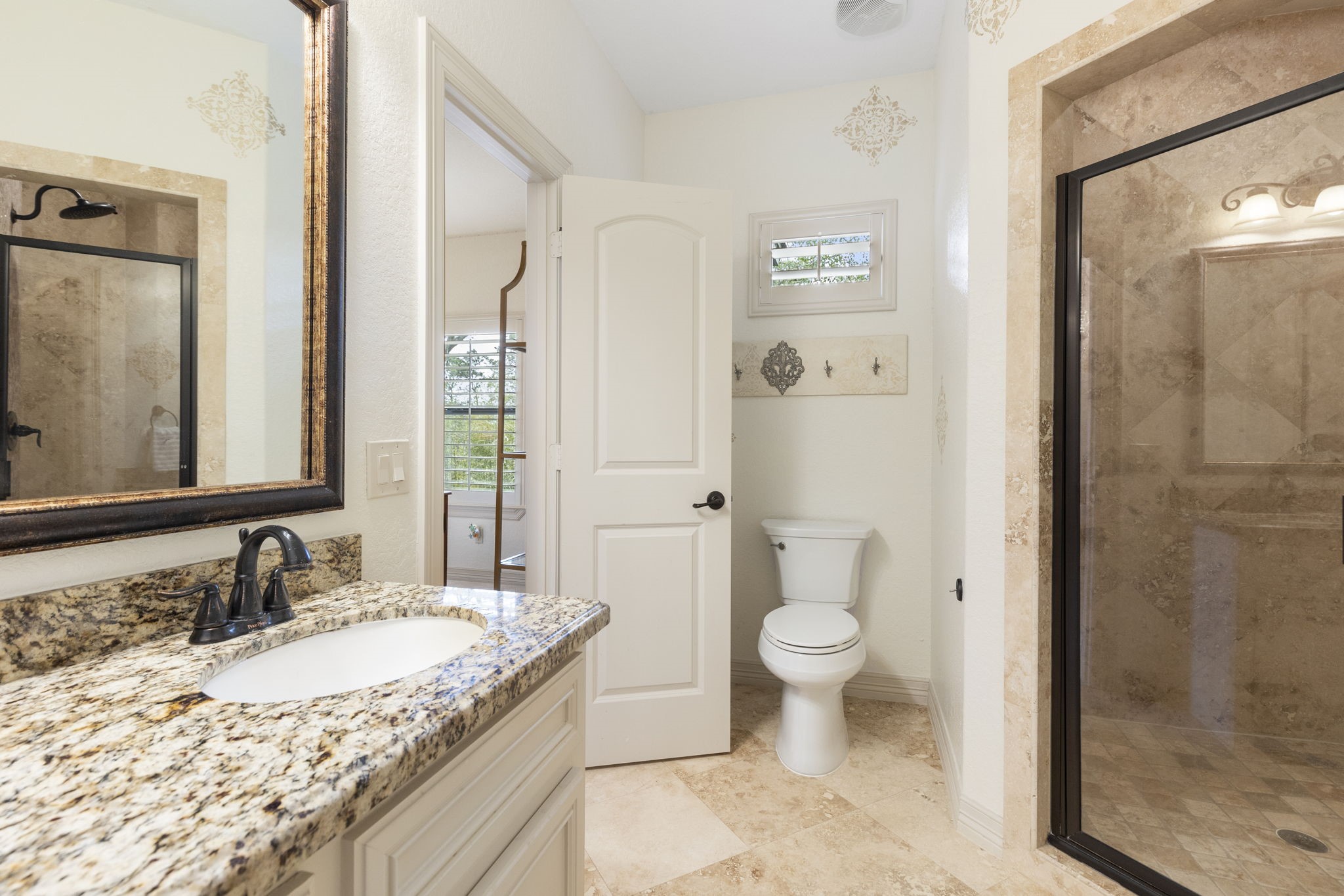 28227 KAILEES Court Spring, TX 77386 - Photo 31 of 48 Private bath with Travertine flooring, oversized walk-in shower with bench seating, granite vanity with abundant storage, and a large framed mirror.