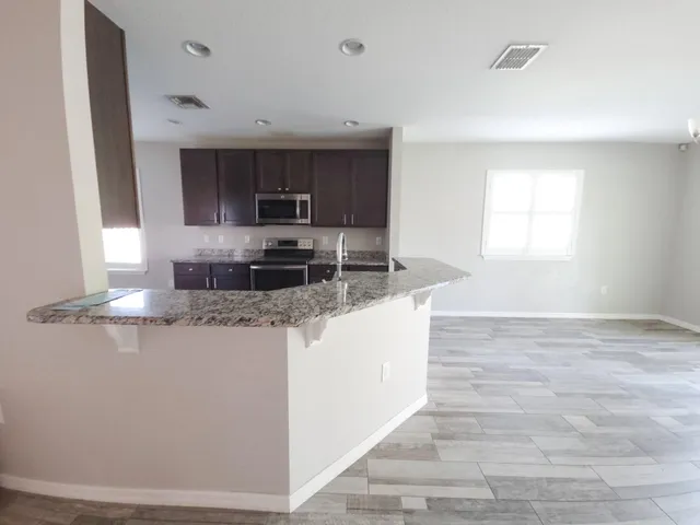 a large kitchen with kitchen island a sink stainless steel appliances and a window