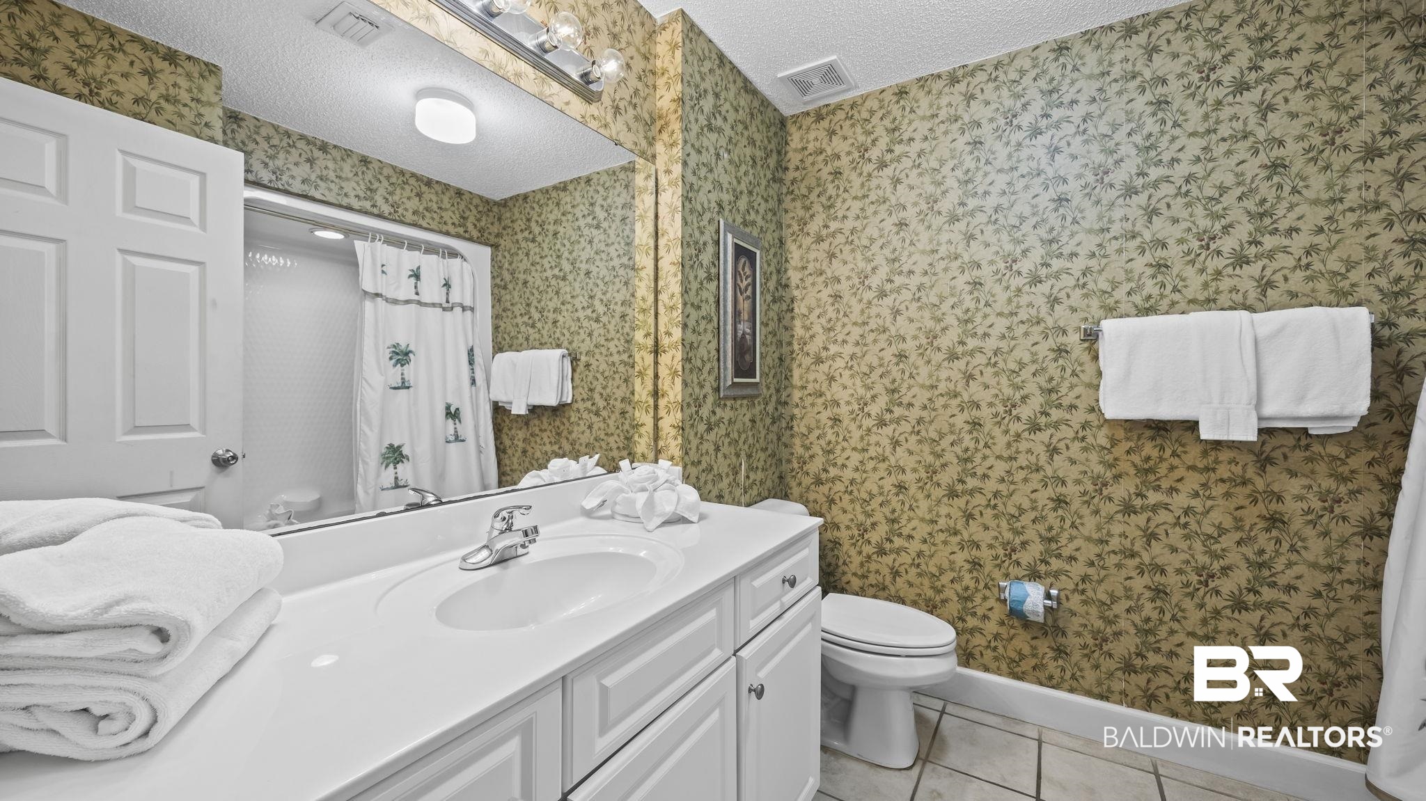 27580 Canal Road, Unit 214 BS 62 Orange Beach, AL 36561 - Photo 14 of 23 Bathroom with a textured ceiling, light tile patterned floors, vanity, and wallpapered walls