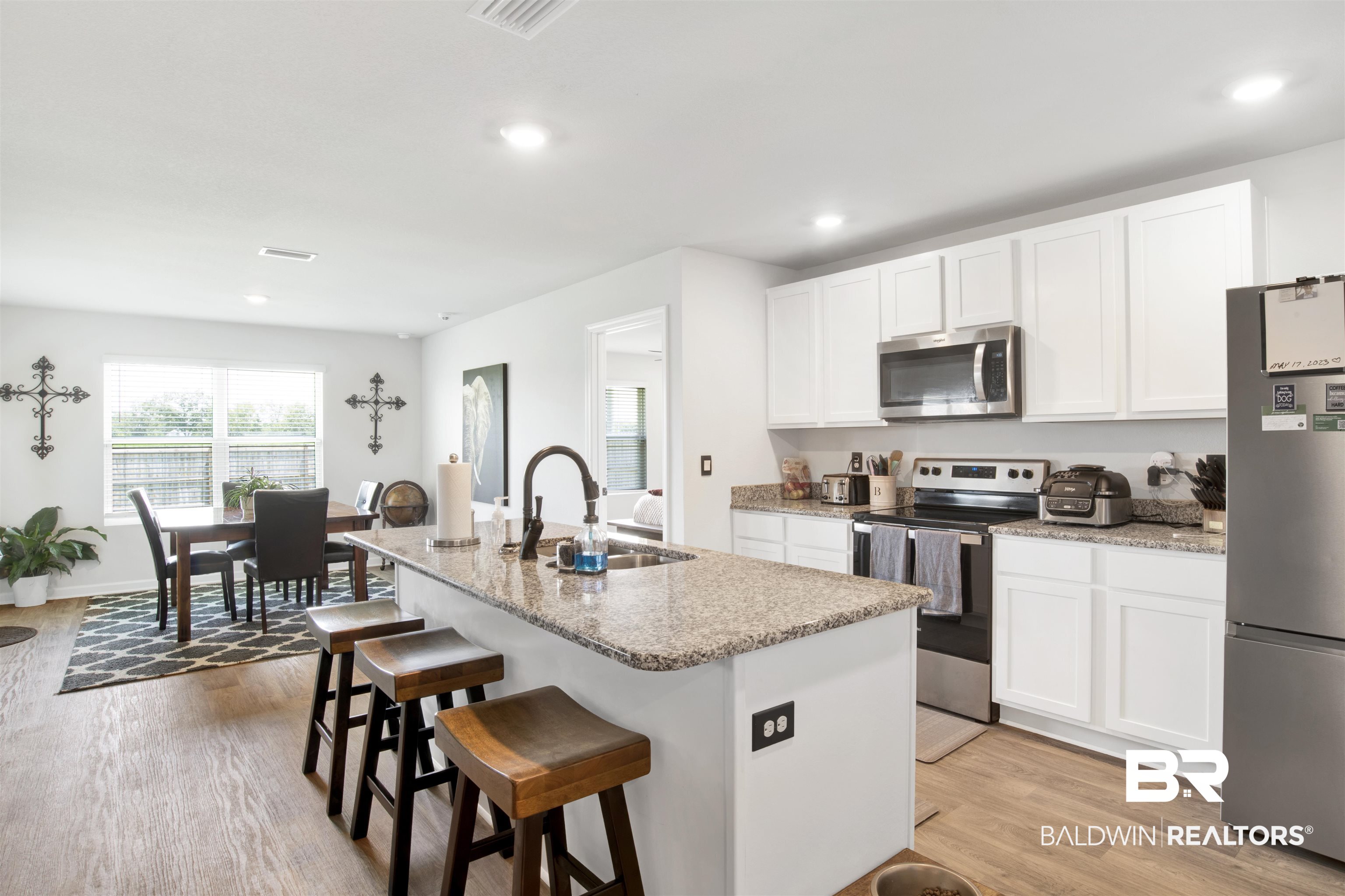 14731 Forsythia Loop Silverhill, AL 36576 - Photo 4 of 25 Kitchen featuring white cabinetry, light wood-type flooring, stainless steel appliances, sink, and a center island with sink