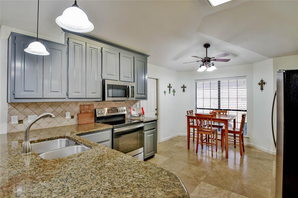 9100 Bellechase Road Granbury, TX 76049 - Photo 22 of 37 a kitchen with stainless steel appliances granite countertop a stove top oven a sink a dining table and chairs with wooden floor