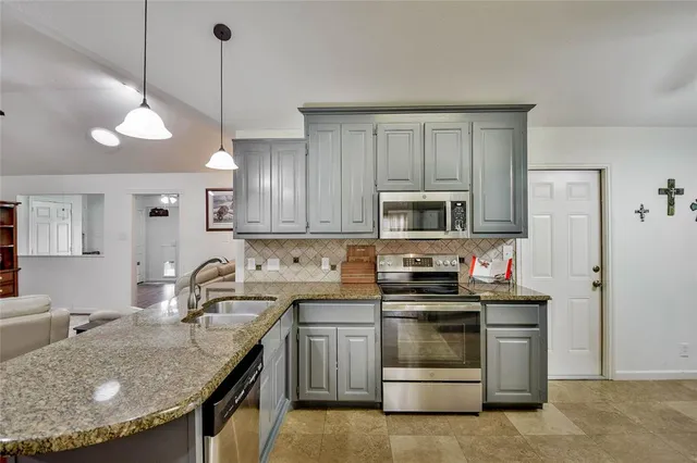 a kitchen with stainless steel appliances granite countertop a stove top oven a sink a dining table and chairs with wooden floor