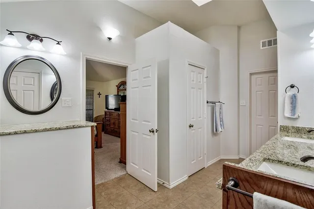 a bathroom with a granite countertop double vanity sink and a mirror
