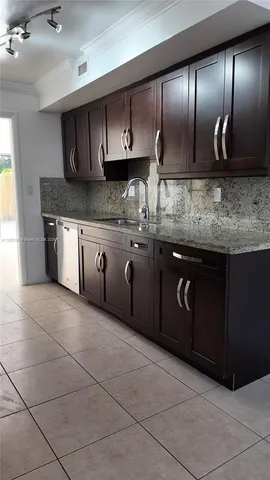 a kitchen with granite countertop a stove a sink and a refrigerator
