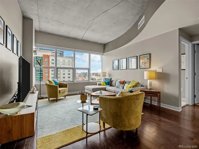 a living room with furniture a flat screen tv and floor to ceiling window