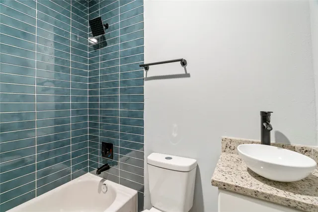 a bathroom with a granite countertop toilet and sink