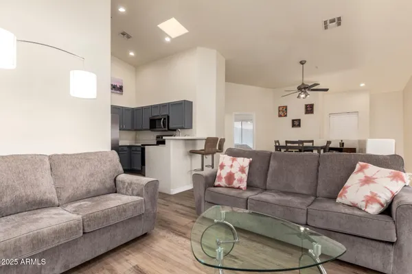 a living room with furniture kitchen view and a chandelier