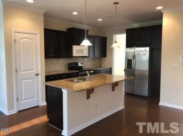 a kitchen with stainless steel appliances granite countertop a refrigerator a sink a stove and oven