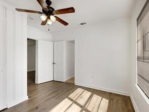 519 Sunnyside Street Cockrell Hill, TX 75211 - Photo 12 of 25 an empty room with wooden floor fan and windows