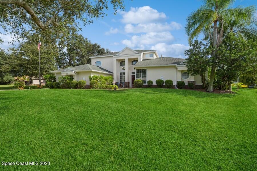 4395 Canard Road Melbourne, FL 32934 - Photo 2 of 36 a view of a white house in front of a big yard with plants and large trees