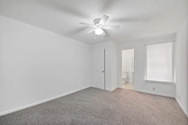 an empty room with closet and a chandelier fan