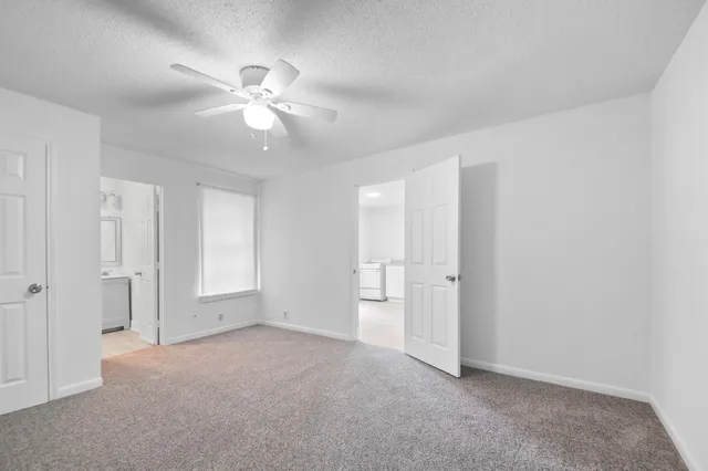 a view of an empty room and chandelier fan