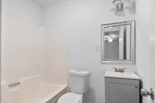 a bathroom with a granite countertop toilet a sink and mirror