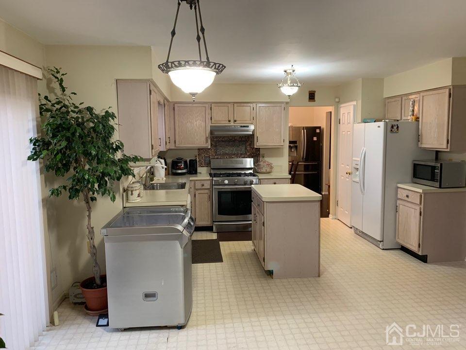 41 Amboy Road Old Bridge, NJ 07747 - Photo 6 of 20 a kitchen with stainless steel appliances a refrigerator a stove a sink a microwave a dining table and chairs