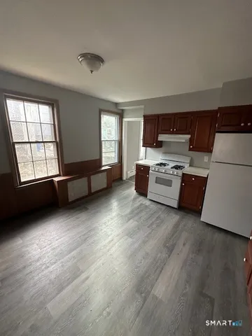 a living room with stainless steel appliances kitchen island granite countertop a stove a refrigerator sink and cabinets