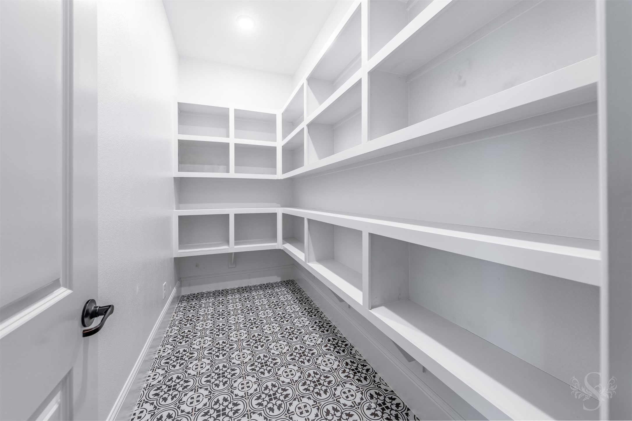 27919 Indigo Ridge Drive Fulshear, TX 77441 - Photo 24 of 50 The oversized walk-in pantry offers extensive built-in shelving, providing exceptional storage for groceries, small appliances, and kitchen essentials. Bright lighting and patterned tile flooring enhance the space, keeping everything organized and within easy reach.