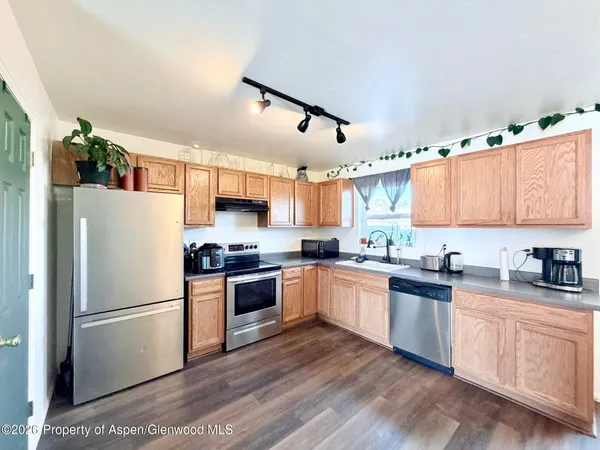a kitchen with stainless steel appliances granite countertop a refrigerator a sink dishwasher a stove and white cabinets with wooden floor