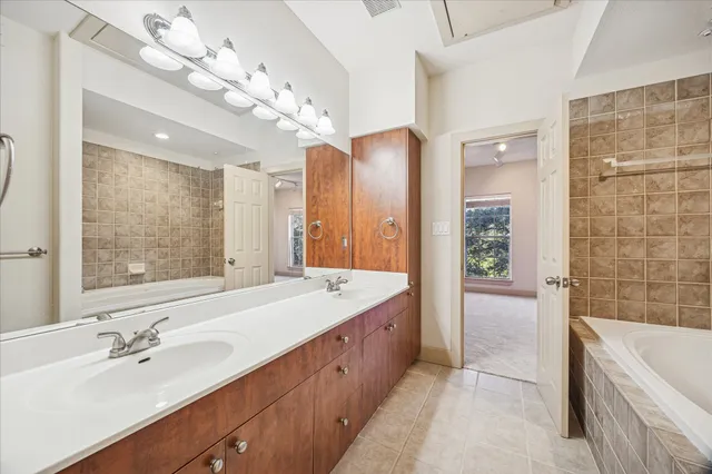 a spacious bathroom with a tub sink shower and mirror