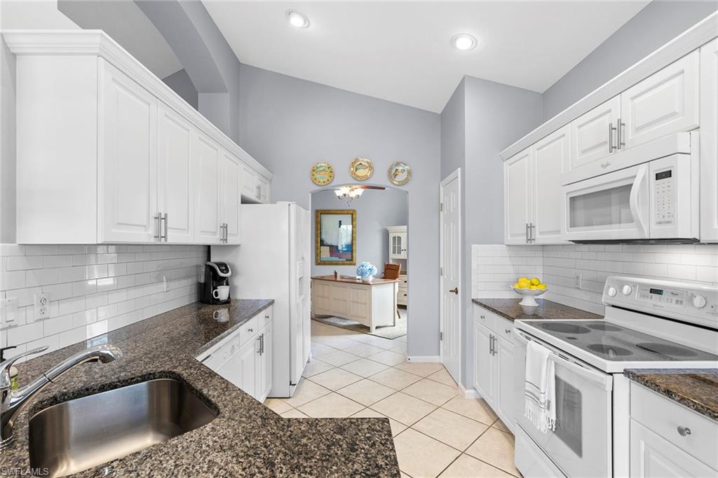 7132 Timberland Circle, Unit 201 Naples, FL 34109 - Photo 8 of 46 a kitchen that has a lot of cabinets in it and wooden floors