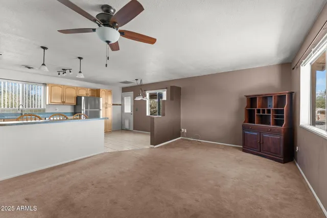 an empty room with chandelier fan and windows