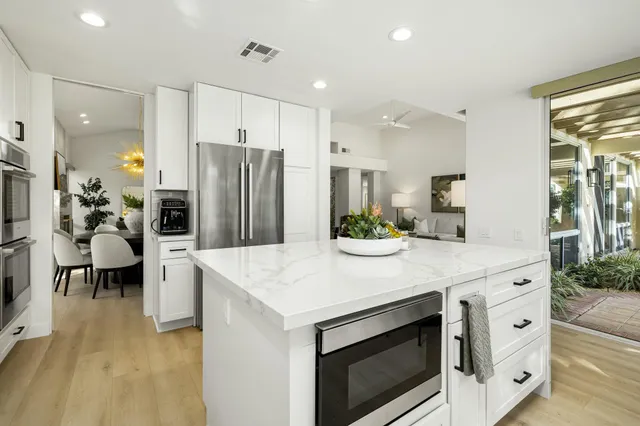 a kitchen that has a lot of cabinets a sink and wooden floor