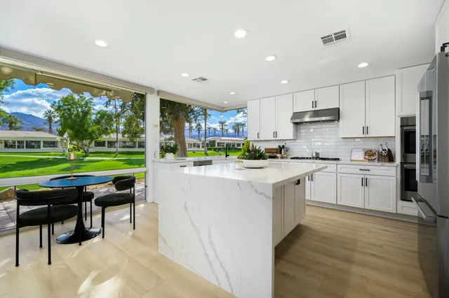 a kitchen with stainless steel appliances kitchen island granite countertop a table and chairs in it