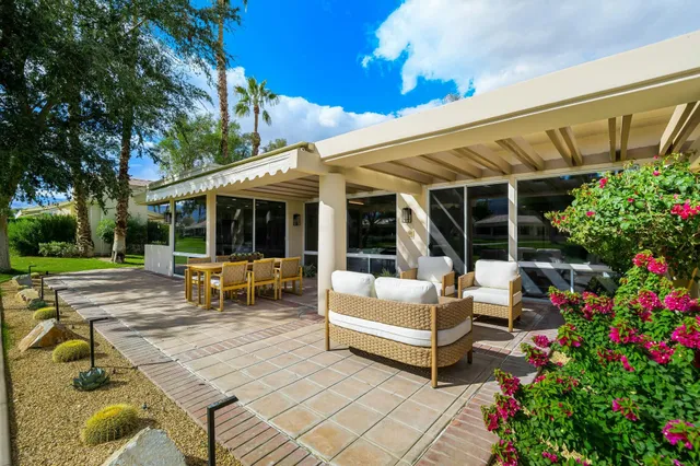 a view of a patio with table and chairs potted plants and large tree