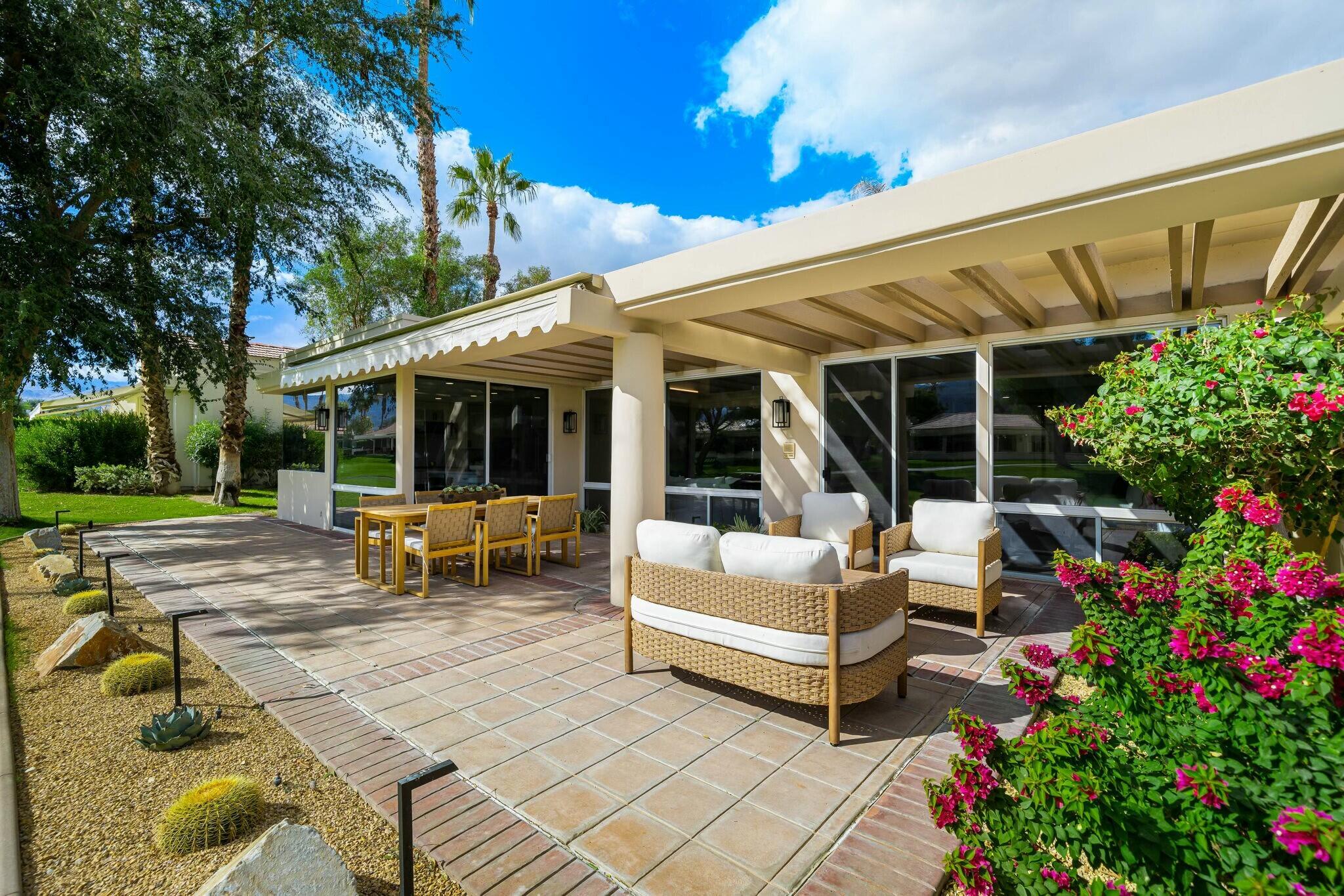 75405 Riviera Drive Indian Wells, CA 92210 - Photo 40 of 43 a view of a patio with table and chairs potted plants and large tree