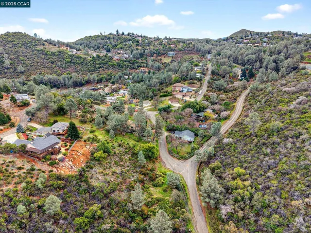 an aerial view of residential house with outdoor space and trees all around
