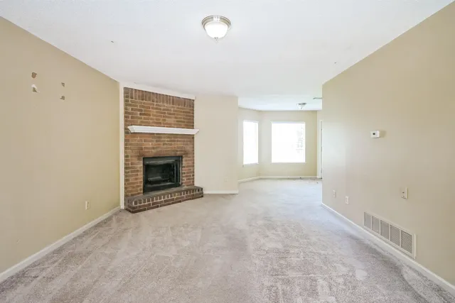 a view of an empty room with a window and a fireplace