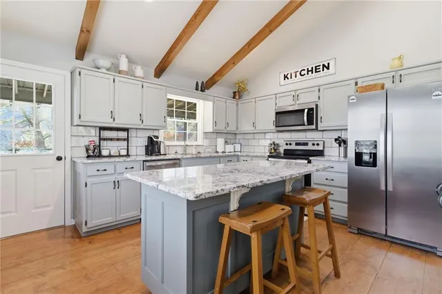 a kitchen with kitchen island granite countertop stainless steel appliances cabinets a sink and a counter top space